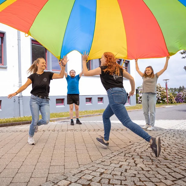 Ergotherapie-Schülerinnen laufen gemeinsam unter einem Schwungtuch. Ergotherapie-Schülerinnen laufen gemeinsam unter einem Schwungtuch.