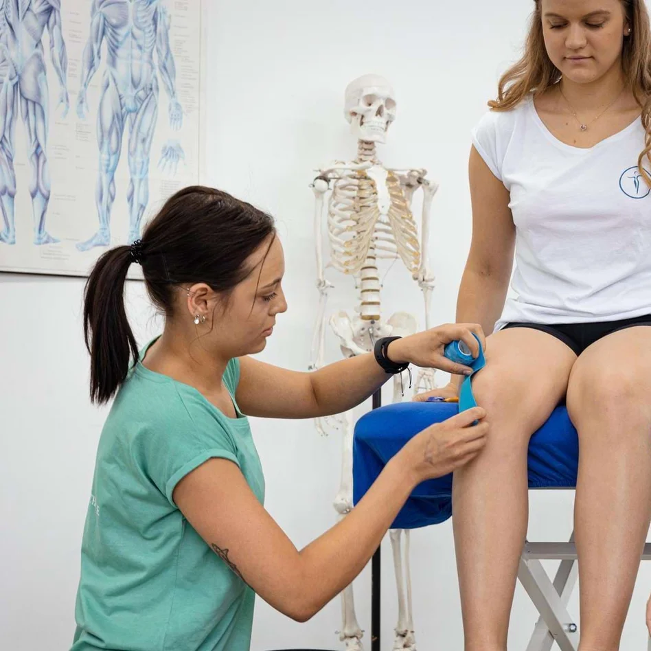 Lehrer zeigt Schülern das Tapen eines Knies in der Physiotherapieausbildung. Lehrer zeigt Schülern das Tapen eines Knies in der Physiotherapieausbildung.