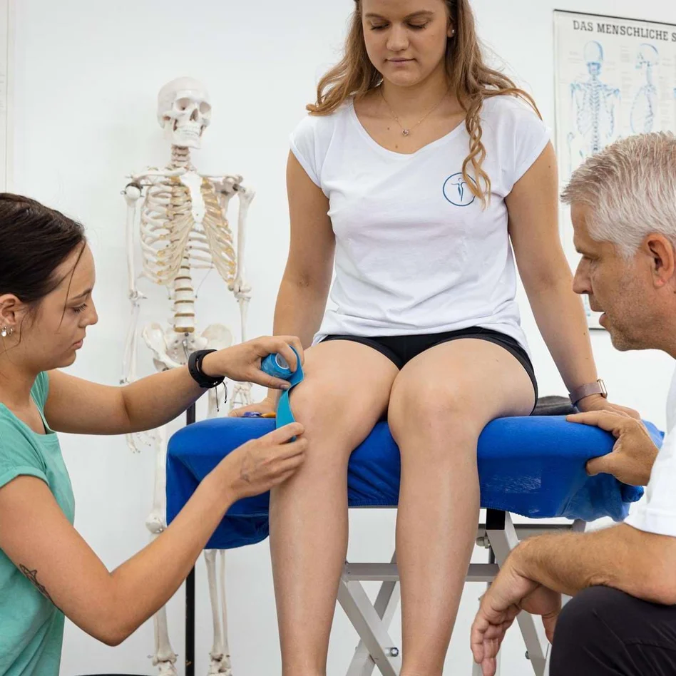 Lehrer zeigt Schülern das Tapen eines Knies in der Physiotherapieausbildung. Lehrer zeigt Schülern das Tapen eines Knies in der Physiotherapieausbildung.