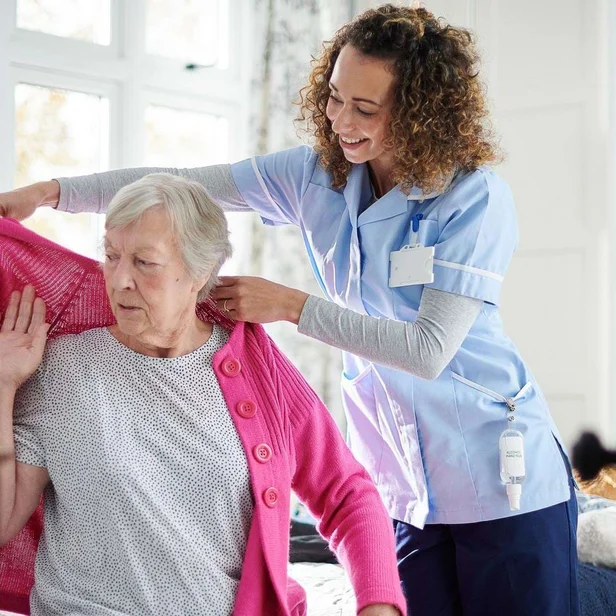 Pflegefachkraft hilft einer Patientin beim Anziehen. Pflegefachkraft hilft einer Patientin beim Anziehen.