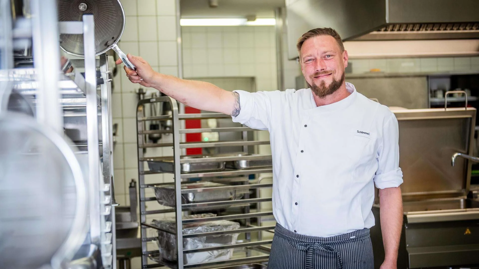 Eric Schimmel steht in der Küche und lächelt in die Kamera. Eric Schimmel steht in der Küche und lächelt in die Kamera.