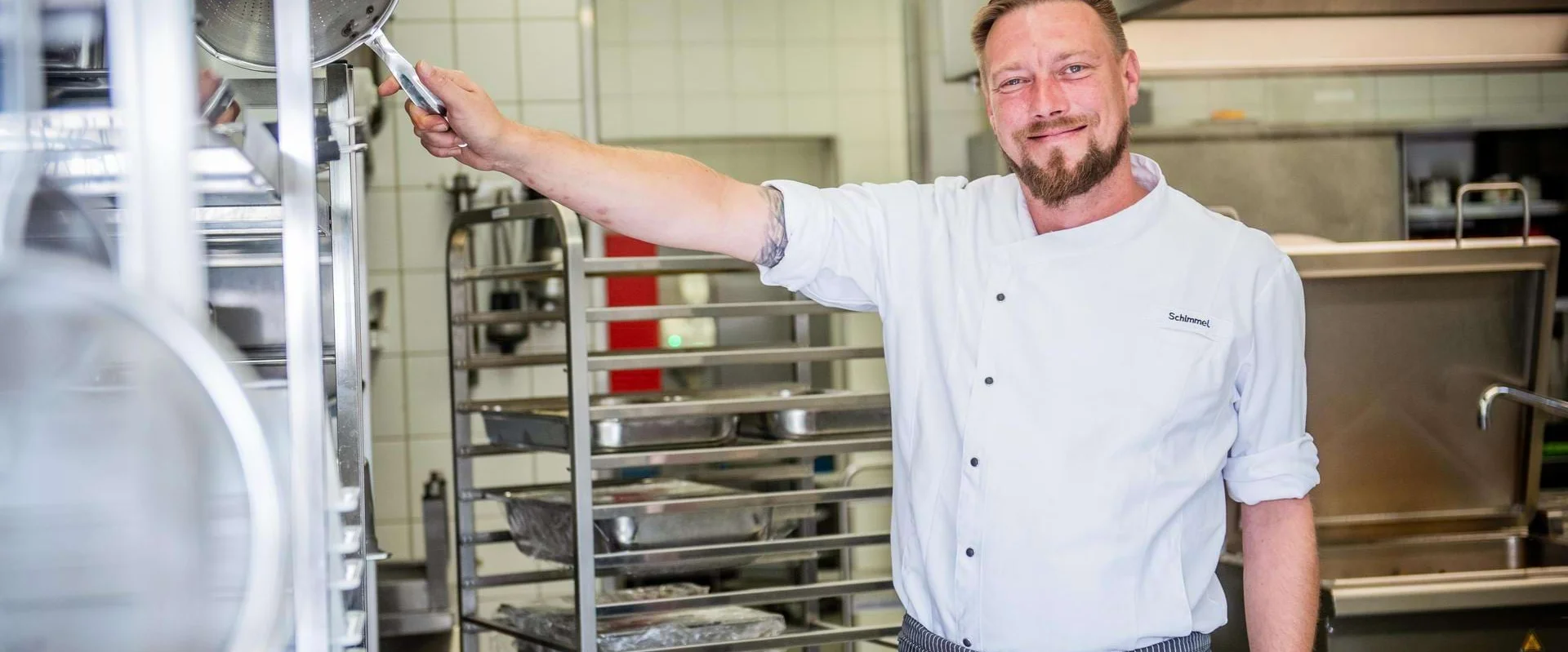 Eric Schimmel steht in der Küche und lächelt in die Kamera. Eric Schimmel steht in der Küche und lächelt in die Kamera.