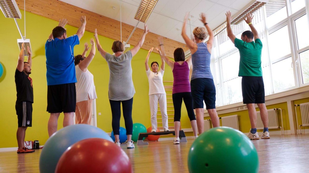 Physiotherapiekurs mit Pezzi Bällen und mehreren Teilnehmern, die im Kreis stehen