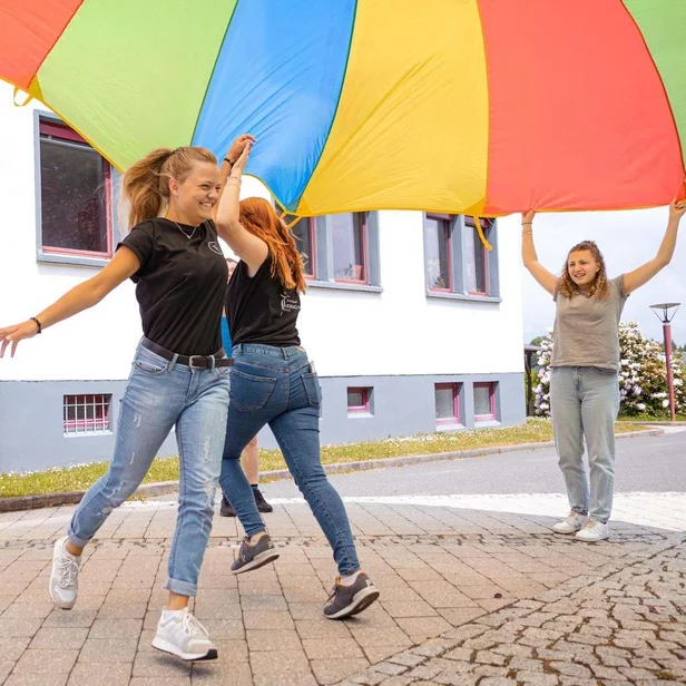 Auszubildende Ergotherapie laufen unter einem Tuch hindurch. Auszubildende Ergotherapie laufen unter einem Tuch hindurch.