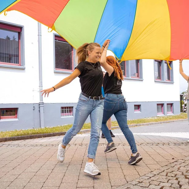 Auszubildende Ergotherapie laufen unter einem Tuch hindurch. Auszubildende Ergotherapie laufen unter einem Tuch hindurch.