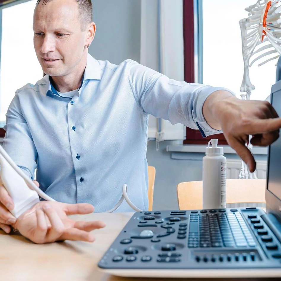 Lehrer erklärt einem Physiotherapie-Schüler eine Ultraschalluntersuchung am Handgelenk. Lehrer erklärt einem Physiotherapie-Schüler eine Ultraschalluntersuchung am Handgelenk.