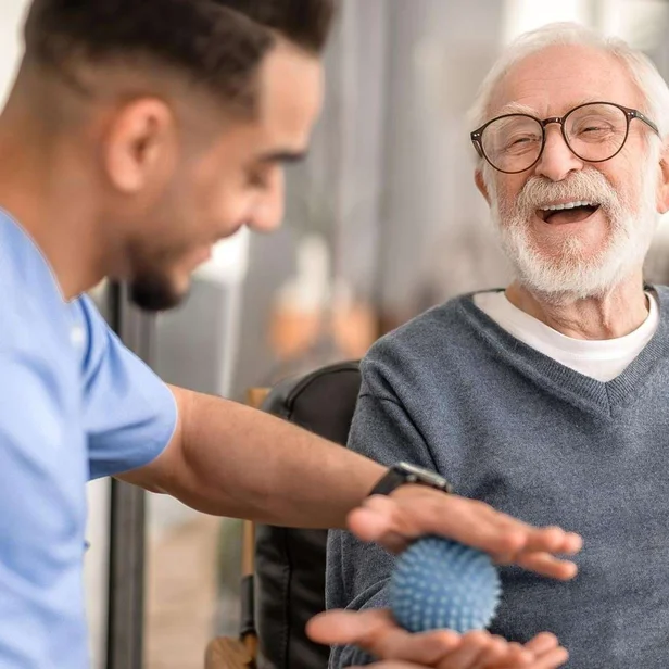 Pflegefachkraft massiert die Hand eines Patienten mit einem Ball. Pflegefachkraft massiert die Hand eines Patienten mit einem Ball.
