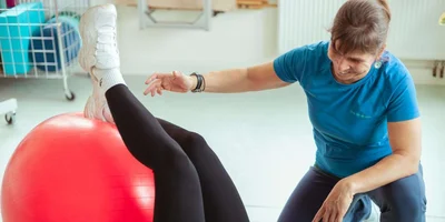 Physiotherapeutin Gesa Heinemann zeigt eine Gleichgewichtsübung mit einem Pezziball.