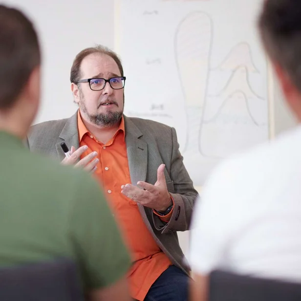 Psychologe leitet ein Gruppengespräch mit mehreren Teilnehmern.