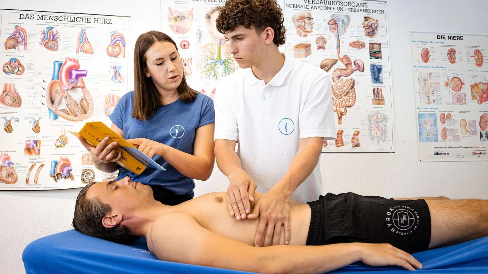 Physiotherapie-Schüler üben gemeinsam eine Behandlung an der Liege. Physiotherapie-Schüler üben gemeinsam eine Behandlung an der Liege., Bild öffnen