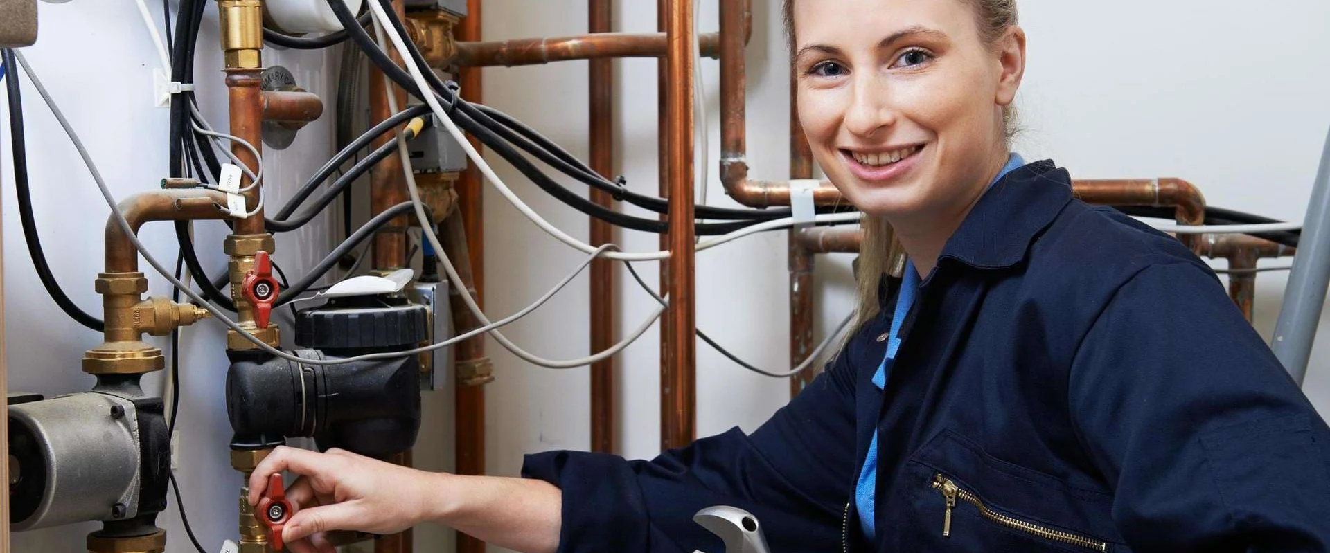 Haustechnikerin arbeitet an Rohrleitungen. Haustechnikerin arbeitet an Rohrleitungen.