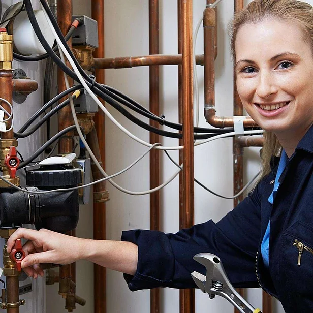 Haustechnikerin arbeitet an Rohrleitungen.
