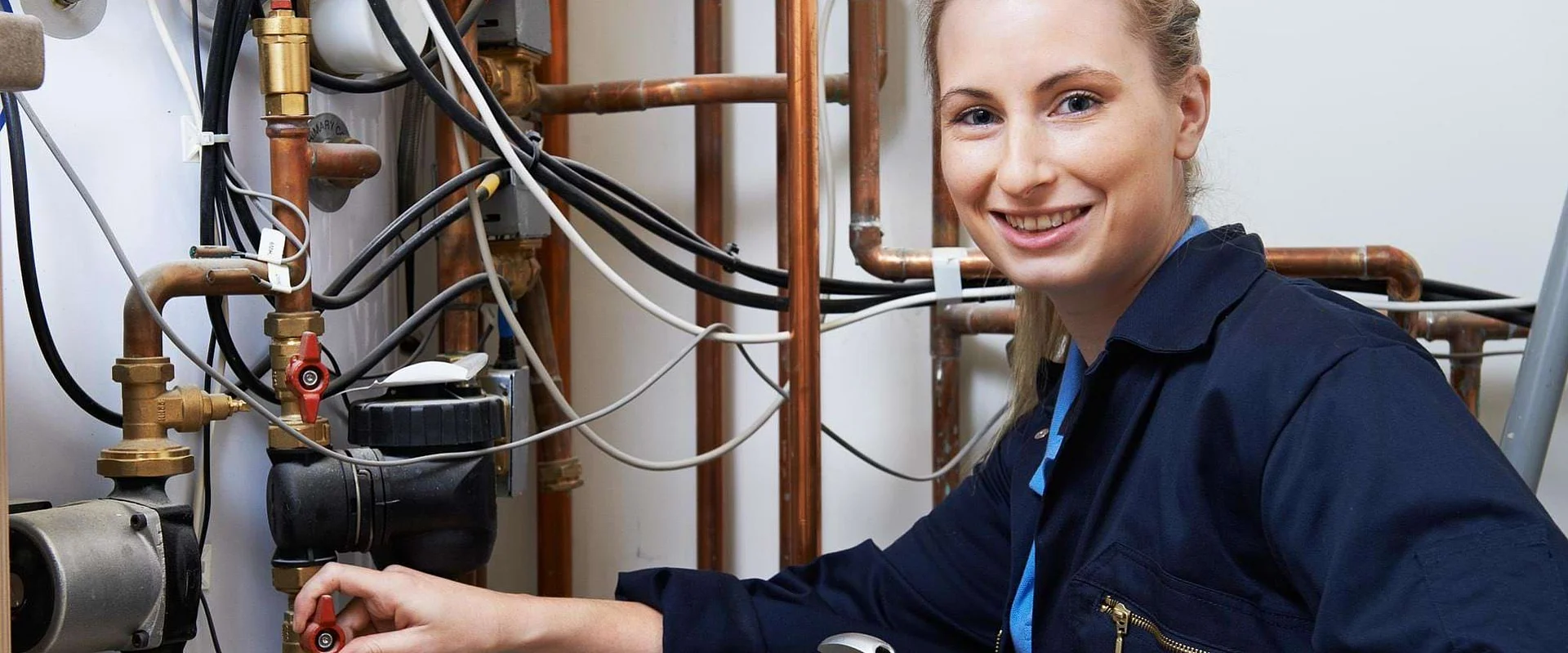 Haustechnikerin arbeitet an Rohrleitungen.