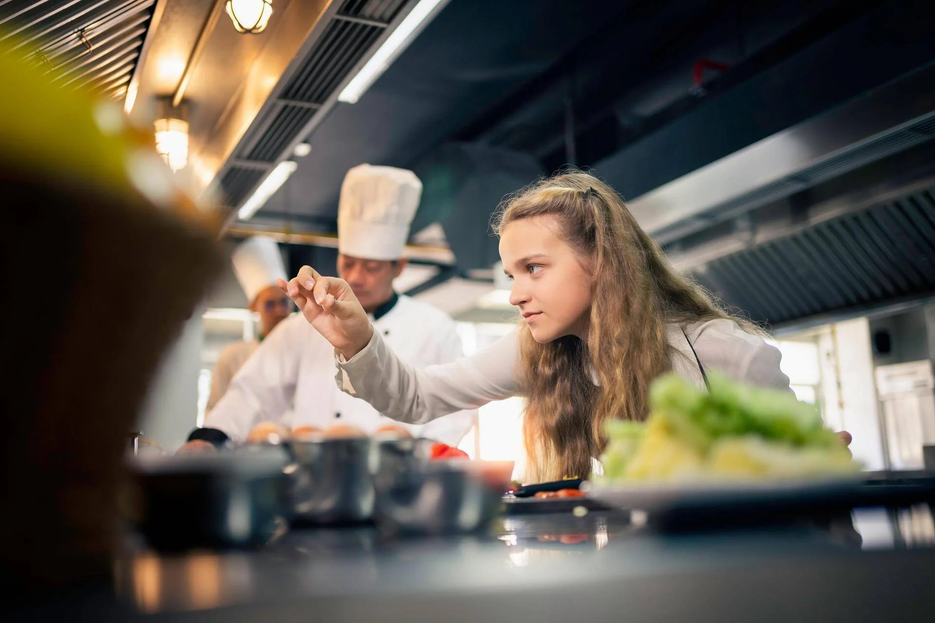 Fachkraft für Restaurants und Veranstaltungsgastronomie würzt Speisen in der Küche. Fachkraft für Restaurants und Veranstaltungsgastronomie würzt Speisen in der Küche., Bild öffnen
