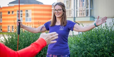 Physiotherapeutin Sarah Wessler zeigt eine aktive Übung zur Schulterbeweglichkeit.