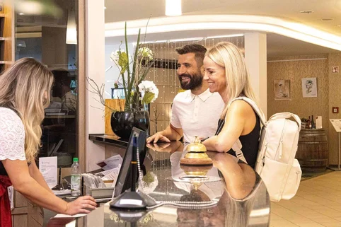 Auszubildende Hotelfachkraft begrüßt Gäste an der Rezeption. Auszubildende Hotelfachkraft begrüßt Gäste an der Rezeption.