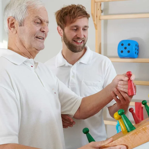 Ergotherapeut macht mit Patienten Geschicklichkeitsübung Ergotherapeut macht mit Patienten Geschicklichkeitsübung