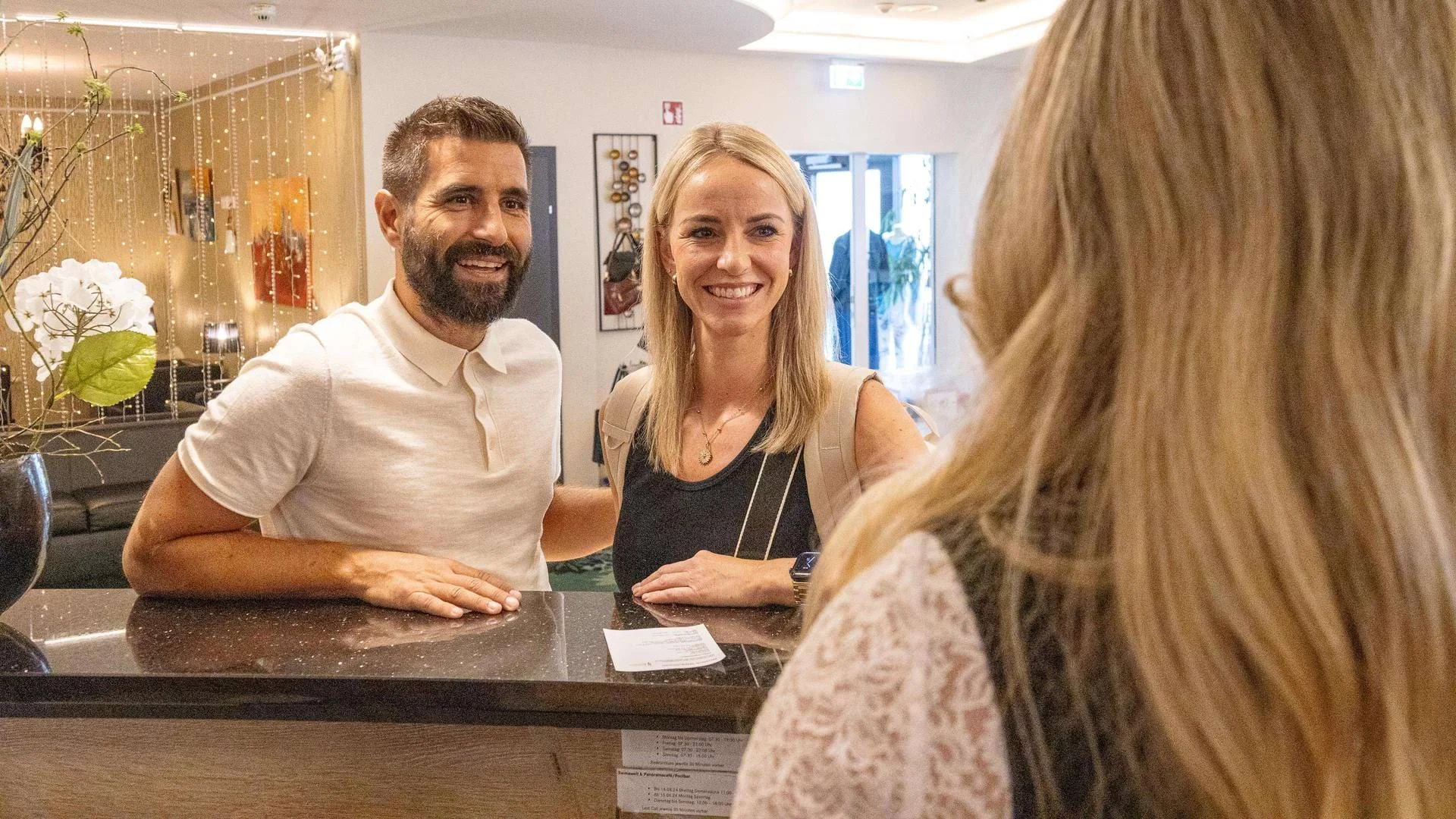 Frau und Mann stehen an Rezeption eines Johannesbad Hotels., Bild öffnen