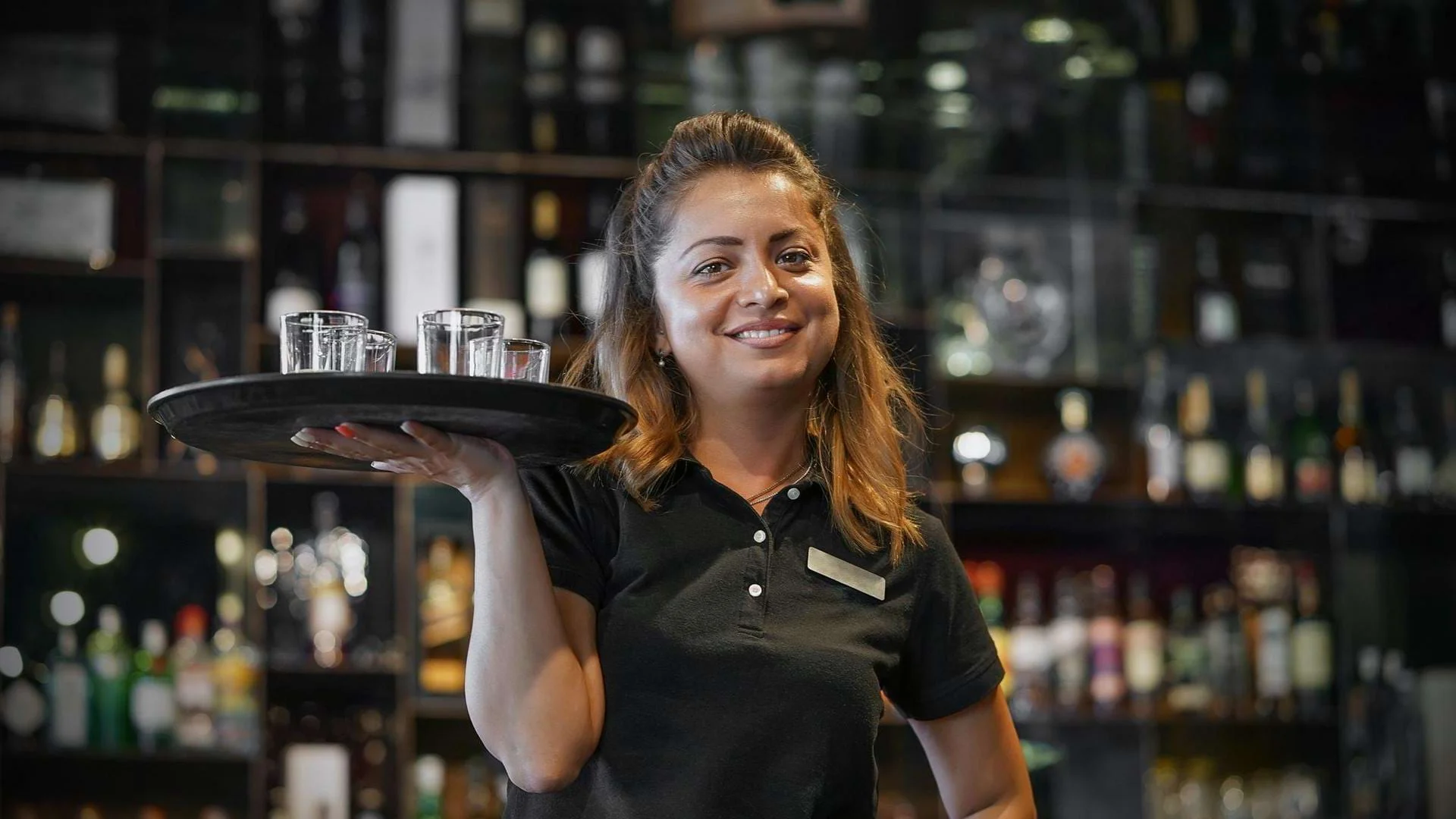 Eine Auszubildende zur Fachkraft für Gastronomie arbeitet mit Tablet im Service., Bild öffnen