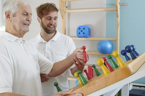 Ergotherapie-Schüler üben mit einem Patienten eine Geschicklichkeitsübung. Ergotherapie-Schüler üben mit einem Patienten eine Geschicklichkeitsübung.