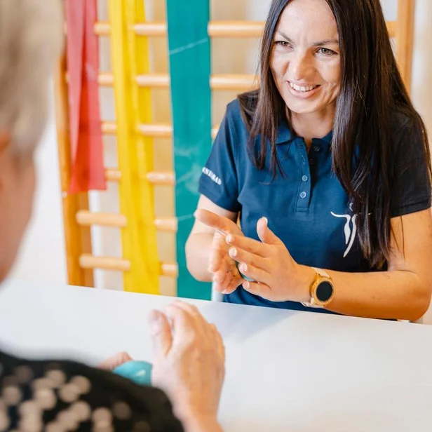 Ergotherapie-Schülerin begleitet eine Patientin bei Handübungen. Ergotherapie-Schülerin begleitet eine Patientin bei Handübungen.