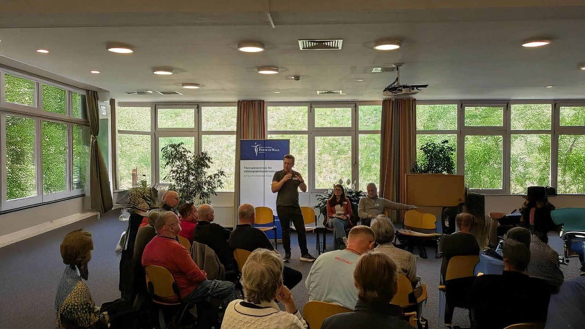 Psychologe Simon Lössl, hält einen Vortrag vor einer Gruppe. Psychologe Simon Lössl, hält einen Vortrag vor einer Gruppe.