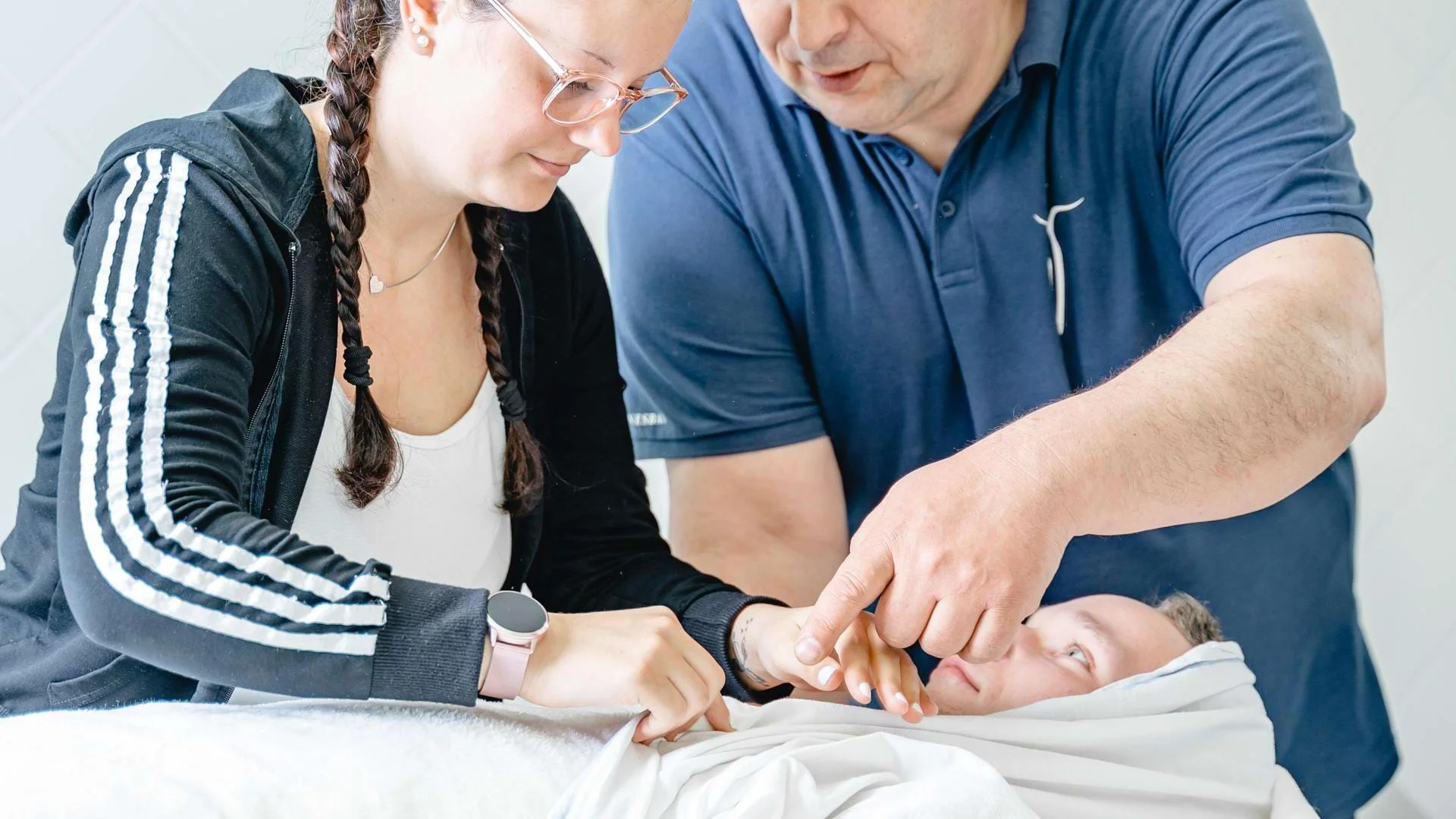 Lehrer erklärt Schülern eine Wickeltechnik in der Ausbildung zum Masseur und medizinischen Bademeister., Bild öffnen
