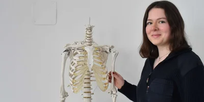 Schülerin Ida Voigt steht neben einem Skelett und lächelt in die Kamera