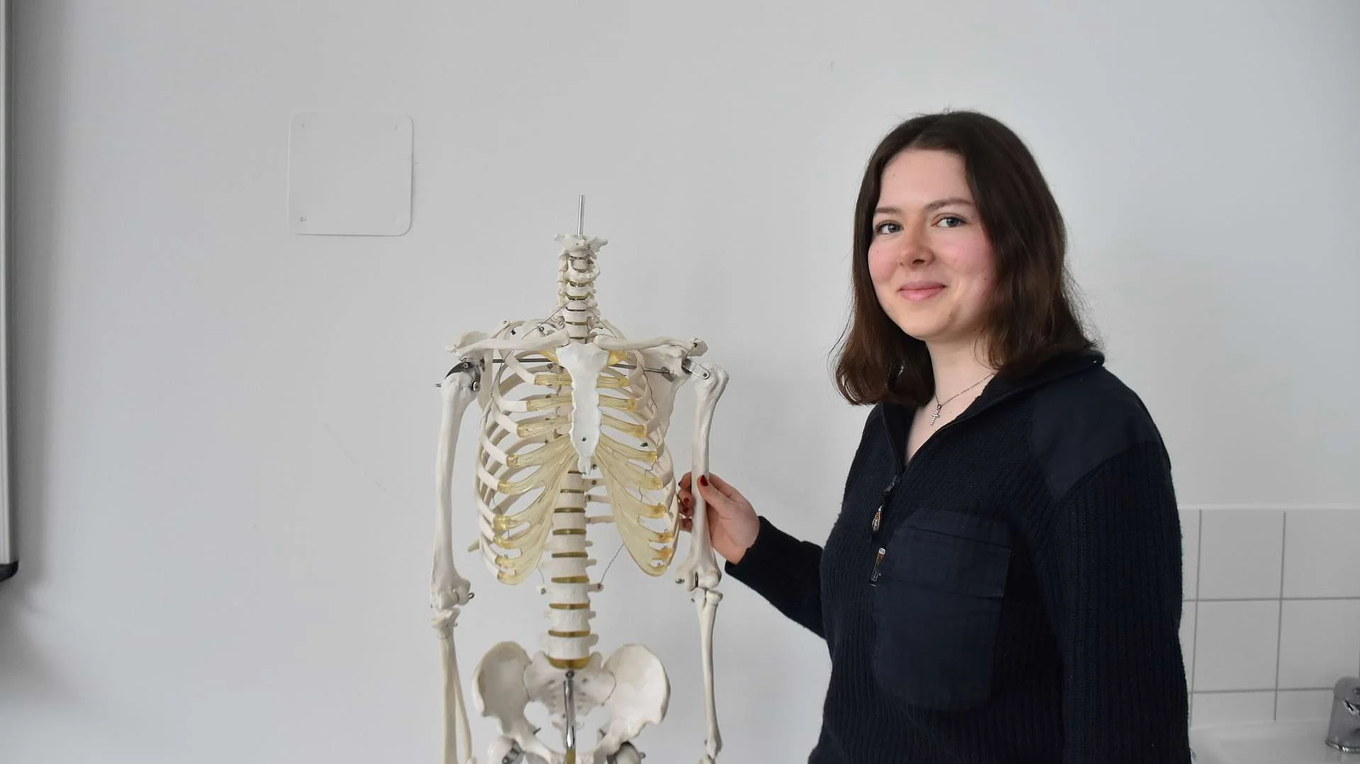 Schülerin Ida Voigt steht neben einem Skelett und lächelt in die Kamera