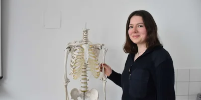 Schülerin Ida Voigt steht neben einem Skelett und lächelt in die Kamera