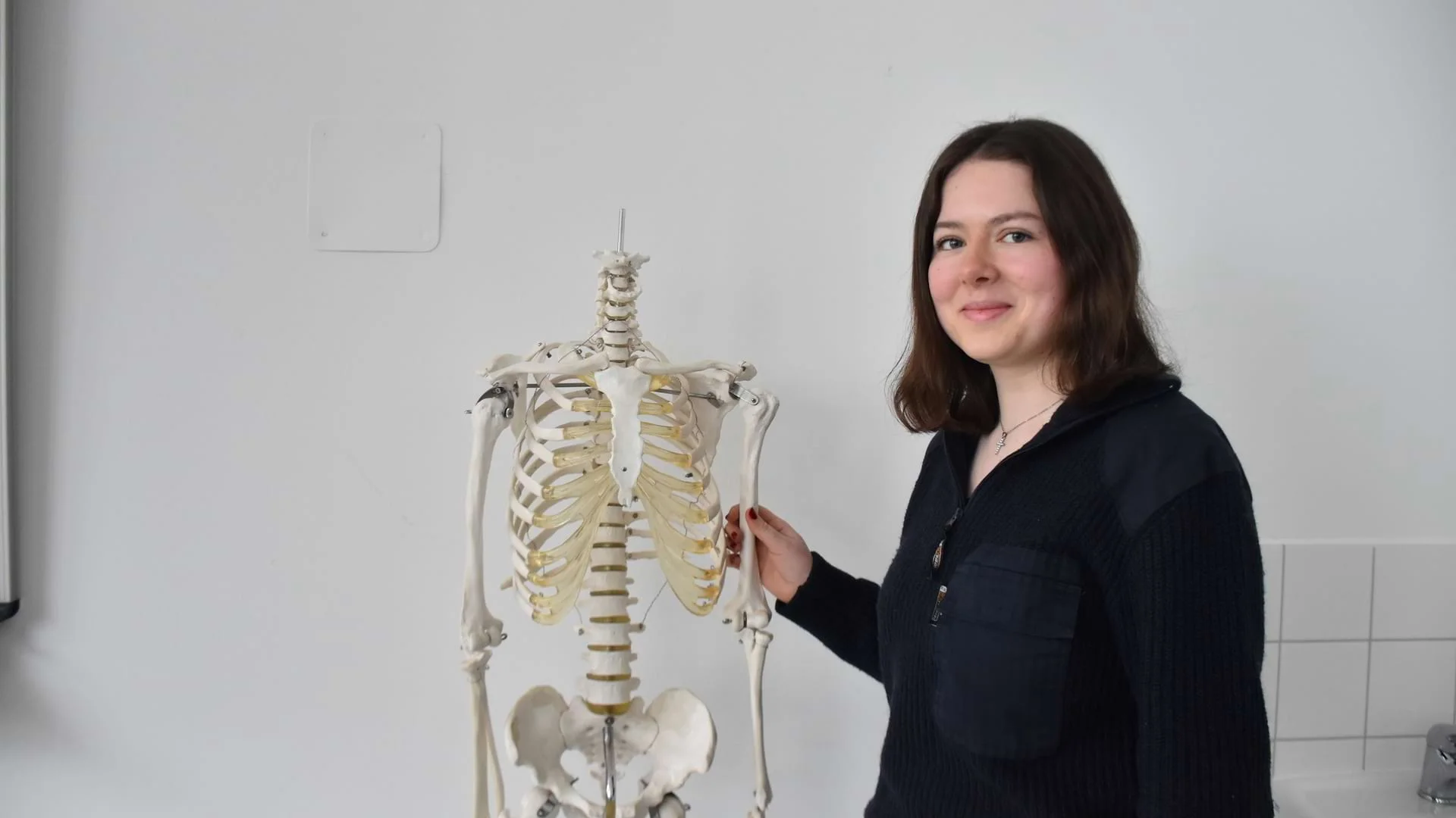 Schülerin Ida Voigt steht neben einem Skelett und lächelt in die Kamera