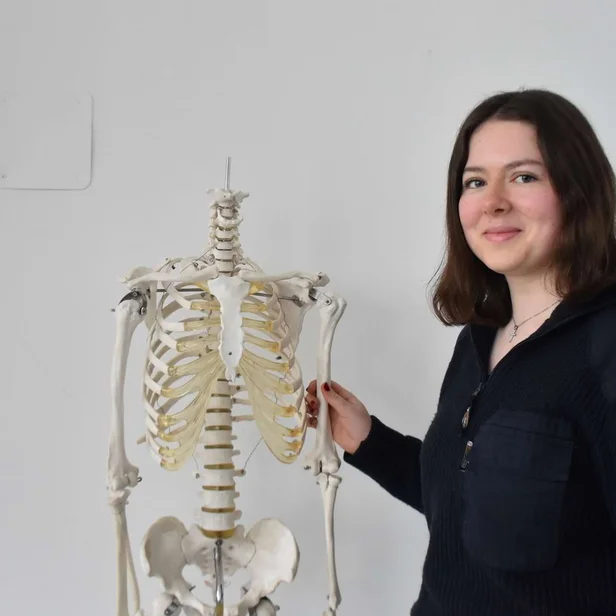 Schülerin Ida Voigt steht neben einem Skelett und lächelt in die Kamera