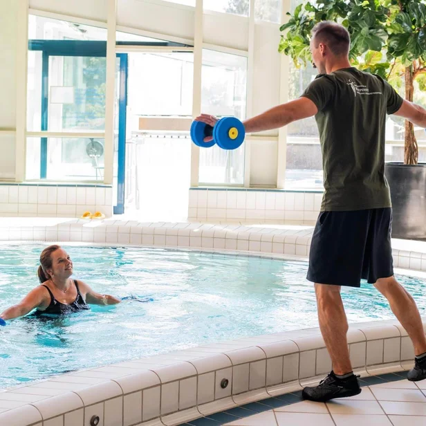 Medizinischer Bademeister leitet einen Aqua-Fitness-Kurs.