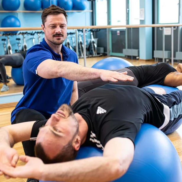 Physiotherapeut begleitet einen Patienten bei Übungen mit dem Pezziball. Physiotherapeut begleitet einen Patienten bei Übungen mit dem Pezziball.
