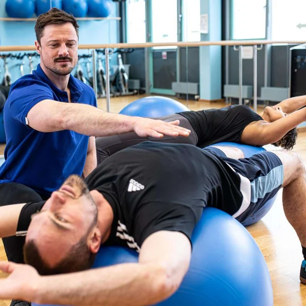 Physiotherapeut begleitet einen Patienten bei Übungen mit dem Pezziball.