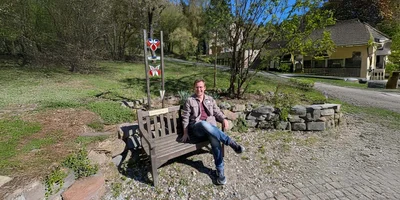Simon Lössl, Psychologe, sitzt auf einer Bank bei der Johannesbad Fachklinik Furth im Wald Simon Lössl, Psychologe, sitzt auf einer Bank bei der Johannesbad Fachklinik Furth im Wald