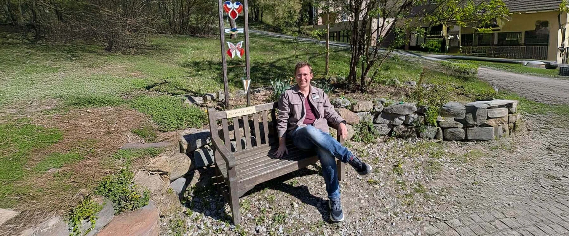 Simon Lössl, Psychologe, sitzt auf einer Bank bei der Johannesbad Fachklinik Furth im Wald Simon Lössl, Psychologe, sitzt auf einer Bank bei der Johannesbad Fachklinik Furth im Wald