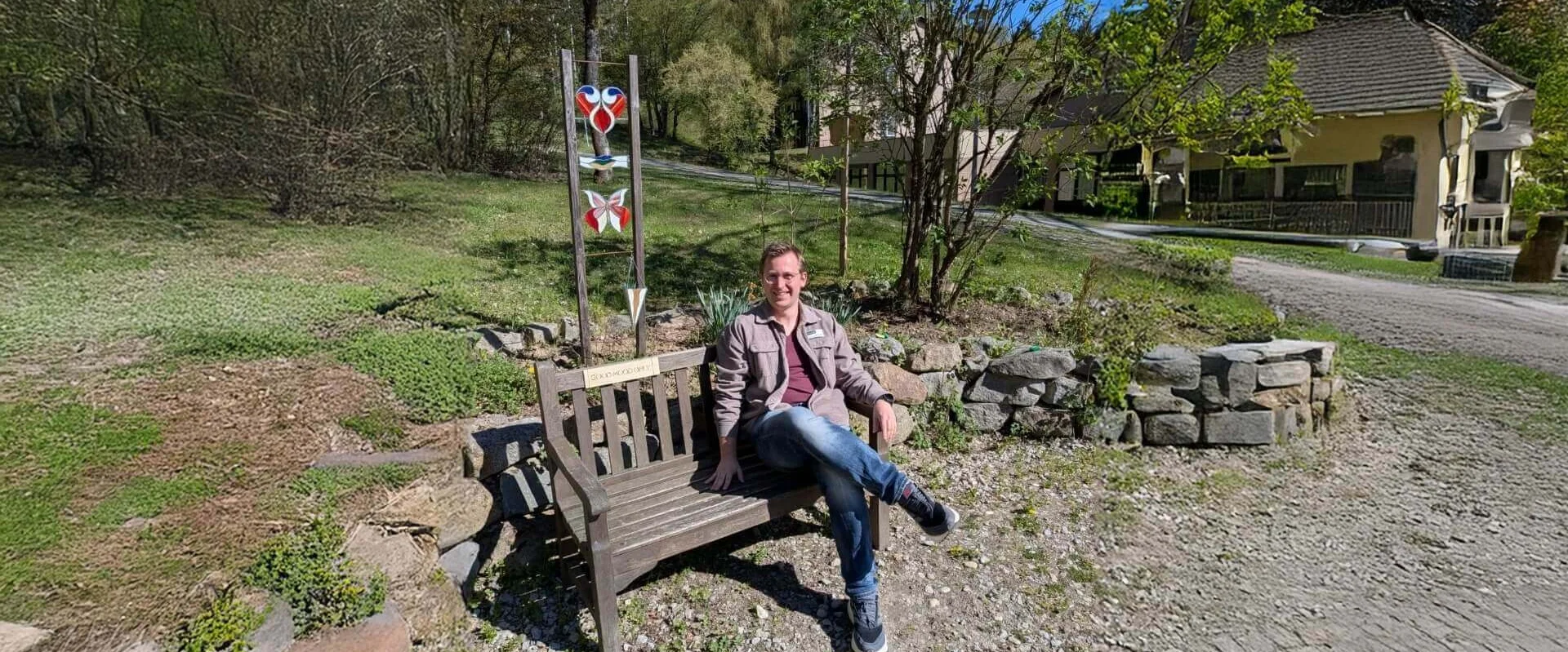 Simon Lössl, Psychologe, sitzt auf einer Bank bei der Johannesbad Fachklinik Furth im Wald