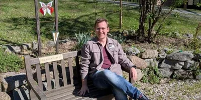 Simon Lössl, Psychologe, sitzt auf einer Bank bei der Johannesbad Fachklinik Furth im Wald