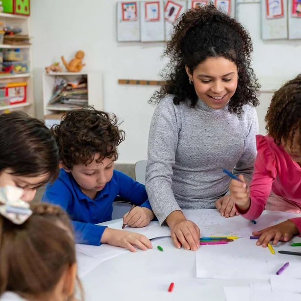Erzieherin malt gemeinsam mit mehreren Kindern. Erzieherin malt gemeinsam mit mehreren Kindern.