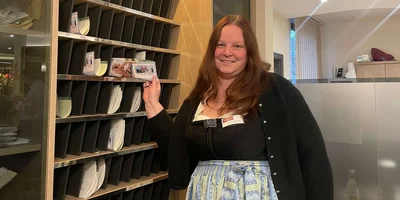 Christina Wichern steht an der Rezeption und lächelt in die Kamera.