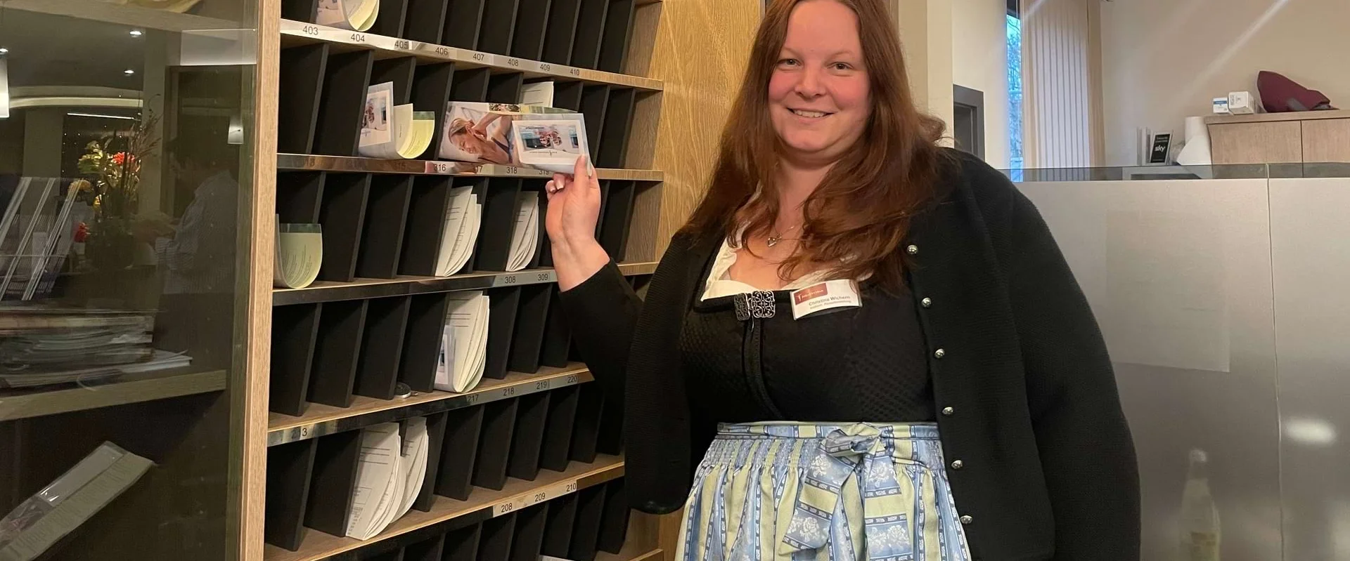 Christina Wichern steht an der Rezeption und lächelt in die Kamera.