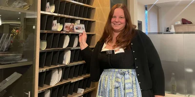 Christina Wichern steht an der Rezeption und lächelt in die Kamera.