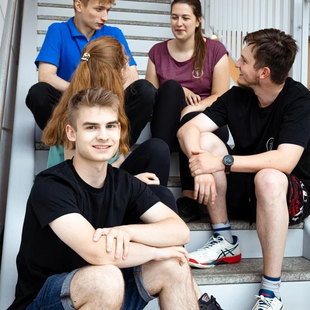 Studierende im dualen Studium Therapie- und Pflegewissenschaften sitzen gemeinsam auf einer Treppe und unterhalten sich. Studierende im dualen Studium Therapie- und Pflegewissenschaften sitzen gemeinsam auf einer Treppe und unterhalten sich.