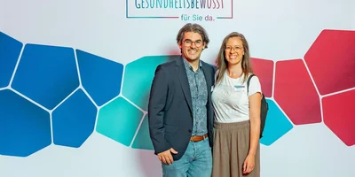 Dr. med  Timo Donate, leitender Oberarzt Johannesbad Fachklinik Saarschleife, mit Kollegin vor Fotowand.