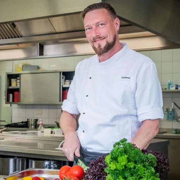 Koch schneidet frische Zutaten in der Küche zu.