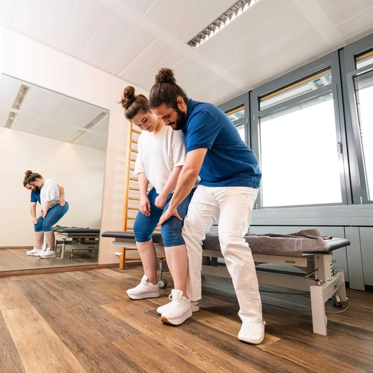 Physiotherapeut erklärt Patientin eine Beinübung