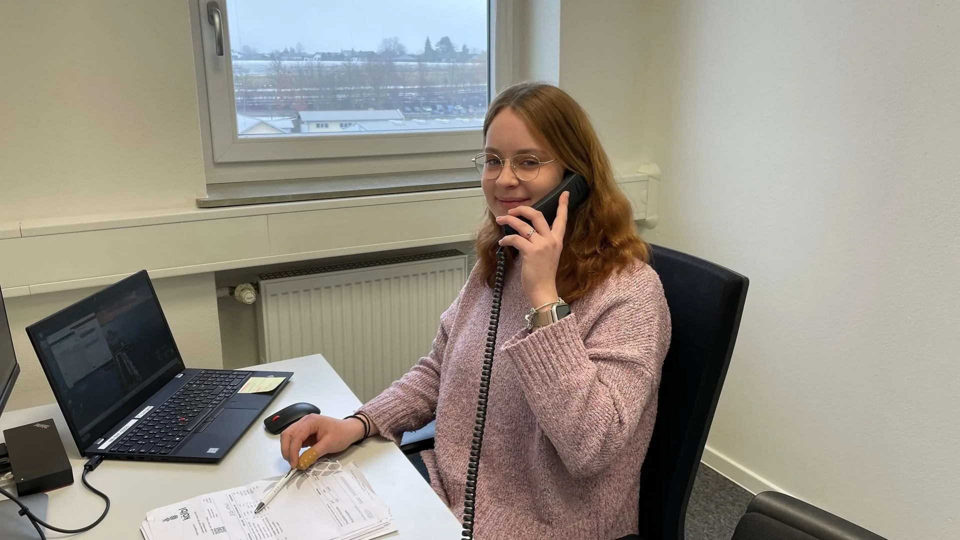 Auszubildende Jana Dietrich telefoniert und blickt in die Kamera