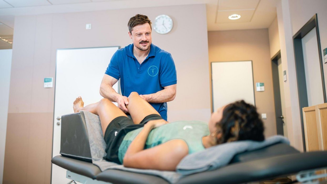Physiotherapeut führt eine Lymphdrainage bei einer Patientin durch.