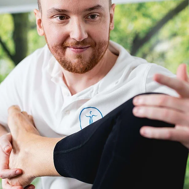 Christian Mahr lächelt einen Patienten an und erklärt eine Übung. Christian Mahr lächelt einen Patienten an und erklärt eine Übung.